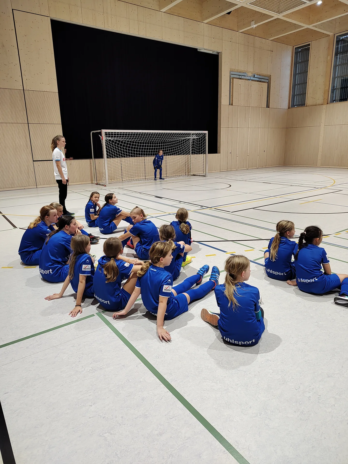 Teilnehmerinnen des Porsche Mädchenfußballcamps 2024 bei einer Besprechung in der Sporthalle