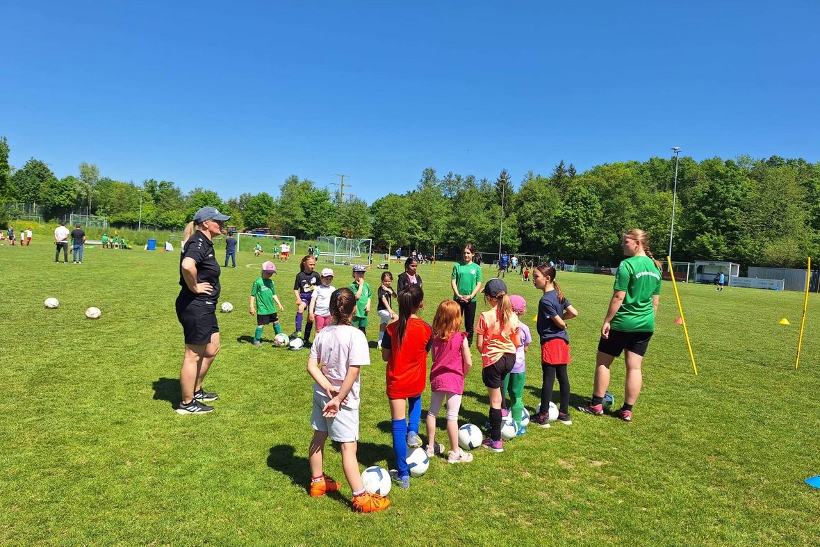 Besprechung einer Mädchengruppe mit Trainerinnen auf dem Fußballplatz
