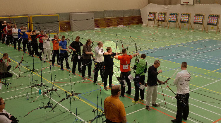 Teilnehmende eines Bogensportwettkampfs in der Halle